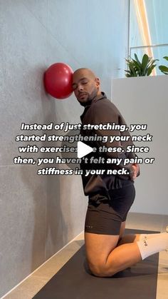 a man sitting on top of a yoga mat next to a wall with a red ball