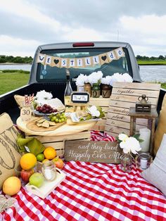 the back of a pick up truck filled with food and drink on top of a checkered table cloth