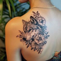 the back of a woman's shoulder with a wolf and flowers tattoo on it