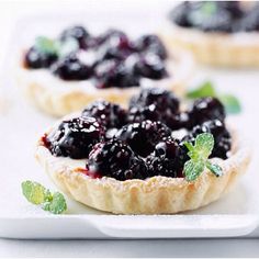 small tarts with blueberries and mint garnish on white serving platter