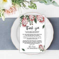 a wedding thank card on top of a plate with flowers and greenery in the background