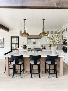 a large kitchen with an island in the middle and four stools at the end