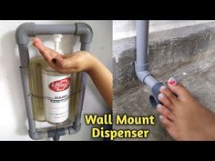 a hand holding onto a wall mounted dispenser next to a person's hand