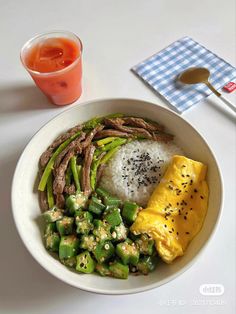 a white bowl filled with rice, meat and veggies next to a drink