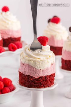 red velvet cupcakes with raspberries and cream frosting on a white cake stand