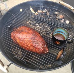 a steak is cooking on the grill with a cup of coffee