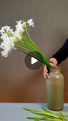 a woman is arranging flowers in a vase