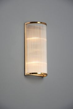 a wall light that is mounted to the side of a gray wall with a white shade on it