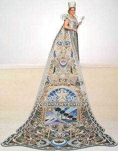 a woman in an elaborate dress standing on top of a carpet