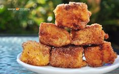 some fried food is stacked on top of each other in a white plate and sitting on a table