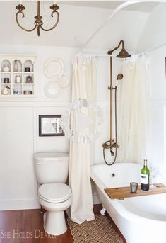 a bathroom with a tub, toilet and chandelier hanging from it's ceiling