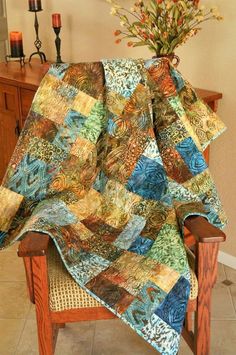 a chair with a quilt on it and a vase full of flowers in the background