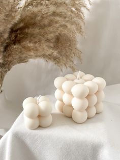 a bunch of white candles sitting on top of a table next to some dried grass