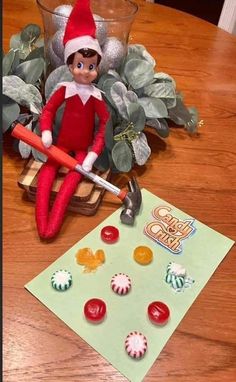 an elf is sitting on top of a table with buttons and a hammer next to it