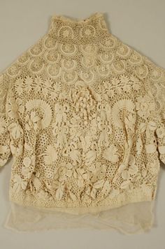 This American or European Irish Crochet blouse from The Met is inventoried as being from 1908. The neck is high, it buttons in the back and has very elaborate textures and shapes complemented by the open work mesh that joins them. Irish Crochet remains a very popular form of lace. The pictures show: the front, a closeup of the front, the back and a closeup of a flower motif and surrounding background. Belle Epoque Fashion, Edwardian Blouse, 1900s Fashion, Evening Blouses, Irish Lace Crochet, Linens And Lace, Costume Collection, Irish Lace, Edwardian Fashion