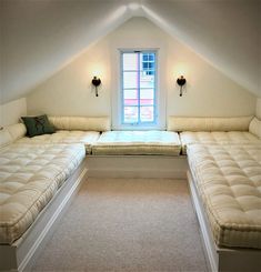 a room with two beds in it and a window above the bed is lit by three lights