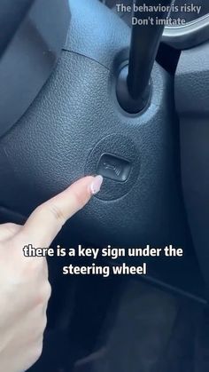 someone is pointing at the steering wheel button on their car, and it says there is a key sign under the steering wheel