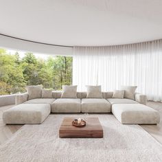 a living room with a large sectional couch in the center and white curtains on the windows