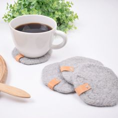 a cup of coffee next to two coasters with wooden spoons