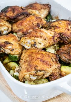 chicken and zucchini in a white casserole dish on a wooden table