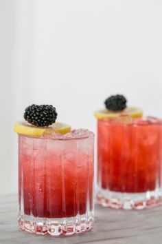 two glasses filled with red liquid and blackberries