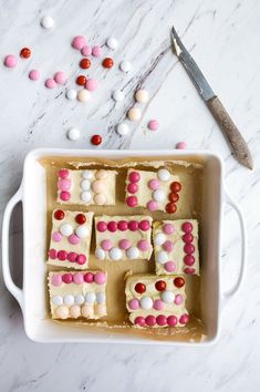 a pan filled with white and pink desserts next to a pair of scissors on top of a table