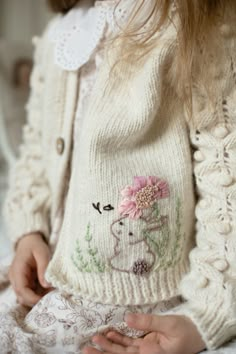 a close up of a person wearing a sweater with flowers on it and a flower in their hair