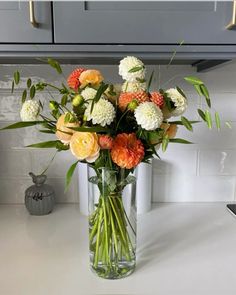 a vase filled with lots of flowers on top of a counter