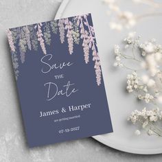 the save the date card is next to some baby's breath flowers on a plate