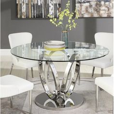 a glass dining table with white chairs around it and a vase on the table top