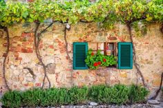 an old building with green shutters and flowers on the window sill in front of it