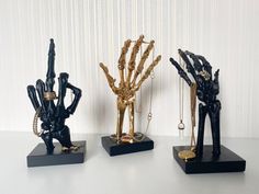 three black and gold hand sculptures sitting on top of a table next to each other