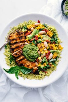 a white plate topped with meat and veggies next to a bowl of sauce