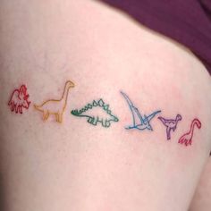 three different colored dinosaurs on the side of a woman's thigh, with one small dinosaur