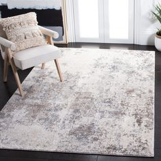 a white and beige rug with a chair in front of it on a black floor