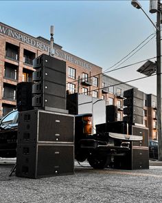 several speakers are stacked on top of each other in front of a building with a street light