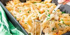 a person scooping some pasta from a casserole dish with cheese and parmesan