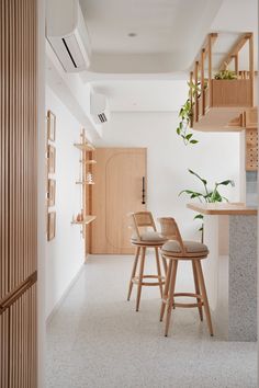 two wooden stools are in the middle of a room with white walls and flooring