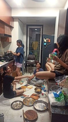 several people sitting on the kitchen counter eating food