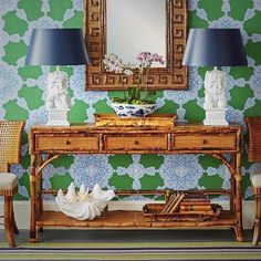 a table with two lamps and a mirror on it in front of a green wall