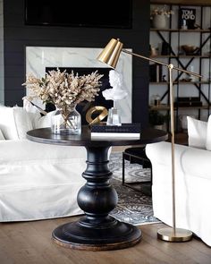 a living room with white couches and a black table in the middle, surrounded by gold accents