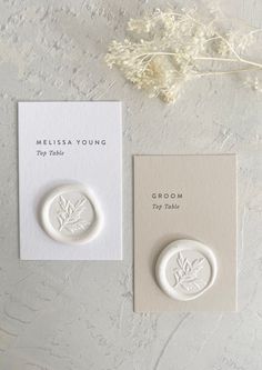 two small white buttons sitting next to each other on top of a card and envelope