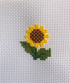 a cross stitch sunflower with green leaves