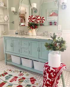 a bathroom decorated for christmas with blue cabinets and white counter tops, red and green decor