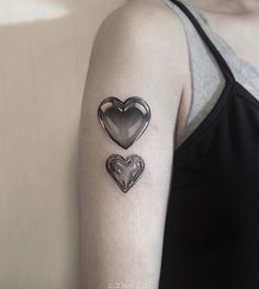 two heart shaped tattoos on the left upper arm and lower arm, both in black and white