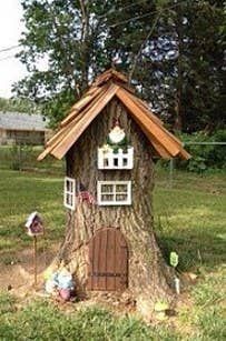 a small tree house built into the side of a tree trunk in a yard with lots of grass and trees around it