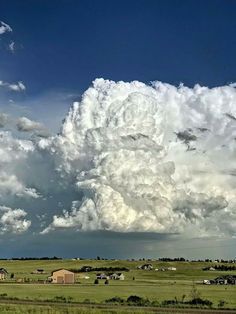 a large cloud is in the sky over a green field