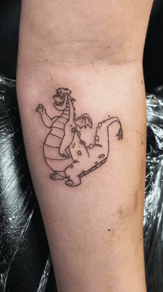 a small tattoo on the leg of a person with a dragon in it's arm