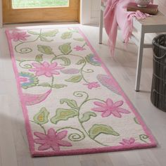 a white rug with pink flowers and green leaves on the floor next to a window