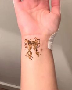 a woman's wrist with a bow tattoo on it